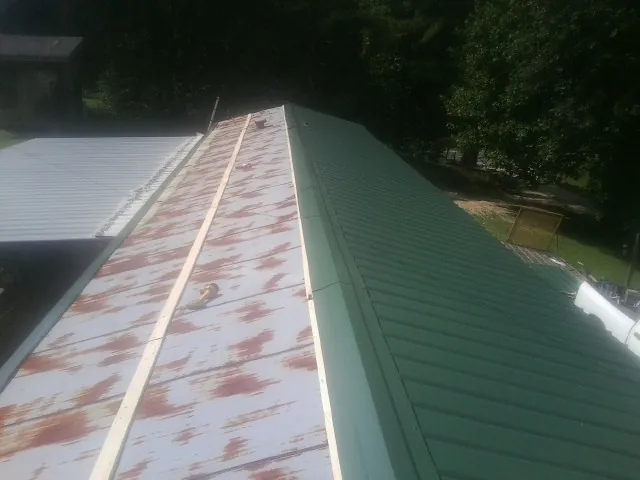 Old rusted panels beside newly installed green metal roofing — Wind Damage Roof Repair by Roofing Brothers in Frankfort